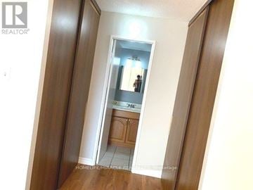 Brampton (Queen Street Corridor) condo for rent - A hallway with a mirror and a door leading to a kitchen.