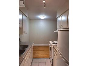 Vancouver apartment for rent - A kitchen with white cabinets and a wooden floor.