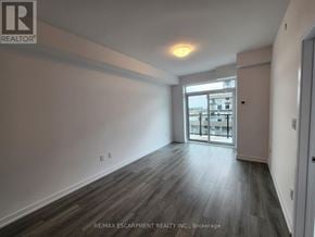 Hamilton (Waterdown) condo for rent - A spacious room with wooden flooring and a large window.