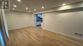 Toronto (Wexford-Maryvale) apartment for rent - A spacious room with wooden flooring and white walls, with a doorway leading to another room visible in the background.