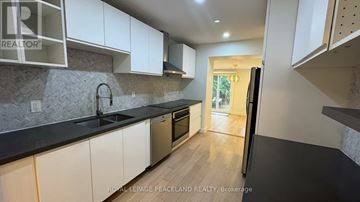 Toronto (Wexford-Maryvale) apartment for rent - A kitchen with white cabinets and a black countertop.