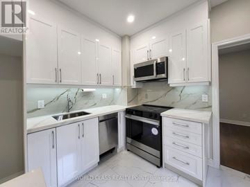 Toronto (Junction Area) duplex for rent - A kitchen with white cabinets and a marble countertop.