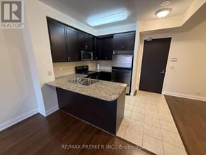 Vaughan (West Woodbridge) condo for rent - A kitchen with dark brown cabinets and a granite countertop.