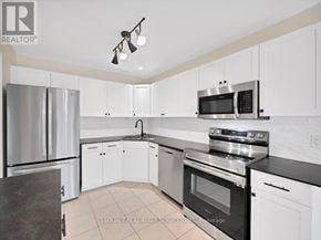 St. Catharines (Rykert/Vansickle) townhouse for rent - A kitchen with white cabinets and black countertops.