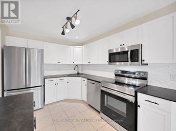 St. Catharines (Rykert/Vansickle) townhouse for rent - A kitchen with white cabinets and black countertops.