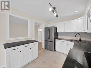 St. Catharines (Rykert/Vansickle) townhouse for rent - A kitchen with white cabinets and a black countertop.