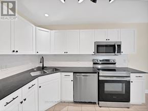 St. Catharines (Rykert/Vansickle) townhouse for rent - A modern kitchen with white cabinets and black countertops.