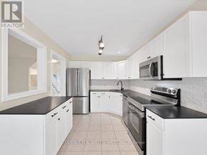 St. Catharines (Rykert/Vansickle) townhouse for rent - A kitchen with white cabinets and black countertops.