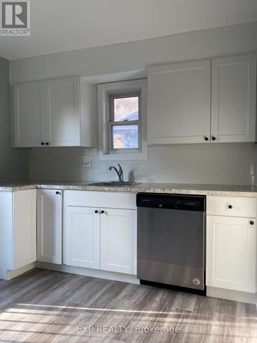 St. Catharines (Downtown) multi-family for rent - A kitchen with white cabinets and a black dishwasher.