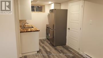 Toronto (Mount Dennis) townhouse for rent - A kitchen with a refrigerator, sink, and cabinets.