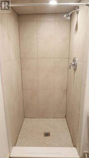 Toronto (Mount Dennis) townhouse for rent - A white tiled shower stall with a drain in the middle.