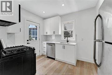Windsor apartment for rent - A kitchen with white cabinets and a black stove top.