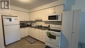 Brantford townhouse for rent - A white refrigerator is in a kitchen with white cabinets.