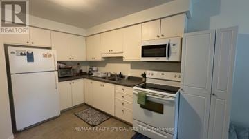 Brantford townhouse for rent - A white refrigerator is in a kitchen with white cabinets.