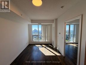 Richmond Hill (Langstaff) condo for rent - A well-lit, empty room with a view of the city through the windows.