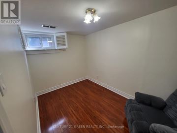 Toronto (West Hill) apartment for rent - A living room with a grey couch and a window with an air conditioner.