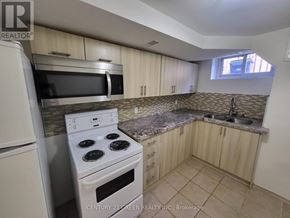 Toronto (West Hill) apartment for rent - A kitchen with a white stove top oven and microwave, wooden cabinets, and a granite countertop.