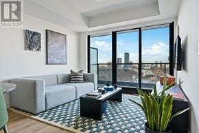 Toronto (Thorncliffe Park) condo for rent - A living room with a grey couch, a coffee table, and a large window with a view of the city.