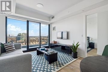 Toronto (Thorncliffe Park) condo for rent - A living room with a grey couch and a black and white checkered floor.