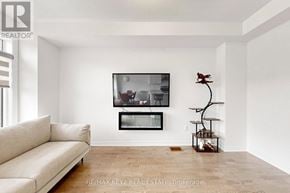 Pickering townhouse for rent - A living room with a couch, a television, and a plant.