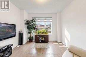 Pickering townhouse for rent - A living room with a flat screen TV, a speaker, a potted plant, and a bookshelf.