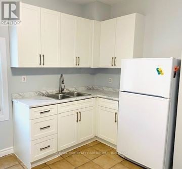 St. Catharines (Oakdale) duplex for rent - A kitchen with white cabinets and a white fridge.