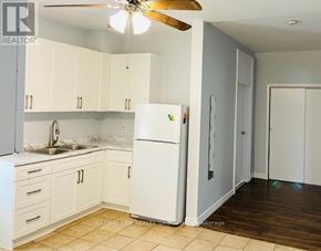 St. Catharines (Oakdale) duplex for rent - A white refrigerator is in the middle of a kitchen with white cabinets.