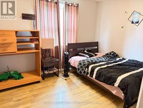 Niagara Falls (Hospital) apartment for rent - A bedroom with a bed, a wooden shelf, and a window with striped curtains.