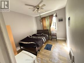 Niagara Falls (Hospital) apartment for rent - A bedroom with a bed, a ceiling fan, and a window with curtains.