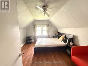 Niagara Falls (Hospital) apartment for rent - A bedroom with a bed, a chair, and a ceiling fan.