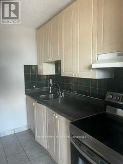 Toronto (Dorset Park) condo for rent - A kitchen with black countertops and beige cabinets.