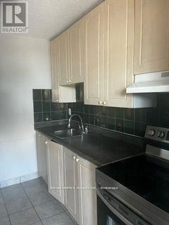 Toronto (Dorset Park) condo for rent - A kitchen with black countertops and beige cabinets.