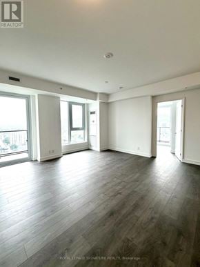 Hamilton (Corktown) condo for rent - A spacious room with wooden flooring and large windows.