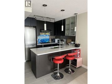 Burnaby apartment for rent - A modern kitchen with a bar stool and a fridge.
