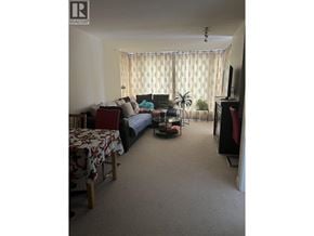 Burnaby apartment for rent - A living room with a couch, a table, a television, and a plant.