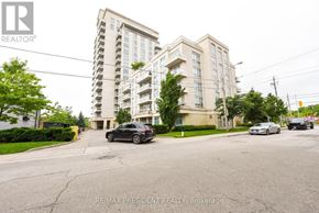 Toronto (Long Branch) condo for rent - A black car is parked on the street in front of a multi-story building.