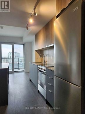 Toronto (Clanton Park) condo for rent - A modern kitchen with stainless steel appliances and a view of the city.