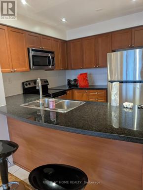 Toronto (Islington-City Centre West) condo for rent - A kitchen with wooden cabinets and a granite countertop.