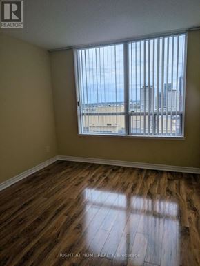 Toronto (Islington-City Centre West) condo for rent - A room with wooden floors and a window overlooking a cityscape.