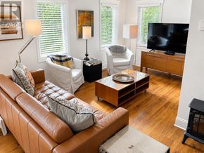 St. John's multi-family for rent - A living room with a brown leather couch and a white chair.