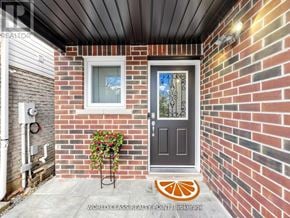 Oshawa (Samac) apartment for rent - A brick house with a grey door and a plant on a stand.
