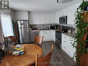 St. Catharines (Downtown) triplex for rent - A kitchen with white cabinets and a wooden table.