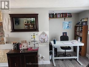 St. Catharines (Downtown) triplex for rent - A room with a desk, chair, and a bookshelf filled with books.