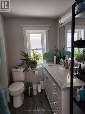 St. Catharines (Downtown) triplex for rent - A bathroom with a toilet, sink, and window.