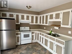 St. Catharines (Oakdale) apartment for rent - A kitchen with white cabinets and a stainless steel refrigerator.