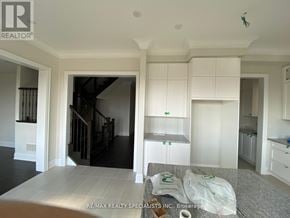 Richmond Hill apartment for rent - A real estate listing photo of a white kitchen with a dining table and a staircase.