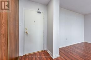 Burlington (Brant Hills) condo for rent - A white door with a gold handle is in a room with wood flooring.
