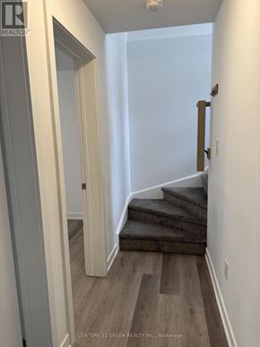 Niagara Falls (Downtown) condo for rent - A hallway with wooden floors and a staircase leading to a second floor.