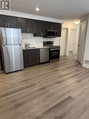Niagara Falls (Downtown) condo for rent - A kitchen with a refrigerator, microwave, oven, and cabinets.