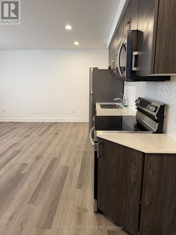 Niagara Falls (Downtown) condo for rent - A kitchen with wooden cabinets and a black stove top oven.
